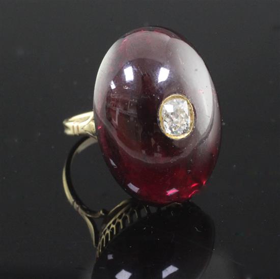 A late Victorian gold and oval cabochon garnet dress ring, with inset old cushion cut diamond, size Q.